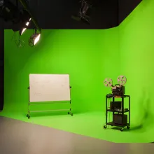 A white board and projector stand sitting on a green screen in a studio.