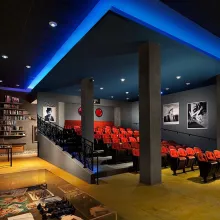Lit up in neon blue, a cinema with plush red seats.